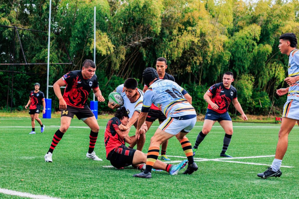 Action-packed rugby game with players tackling on a green field.