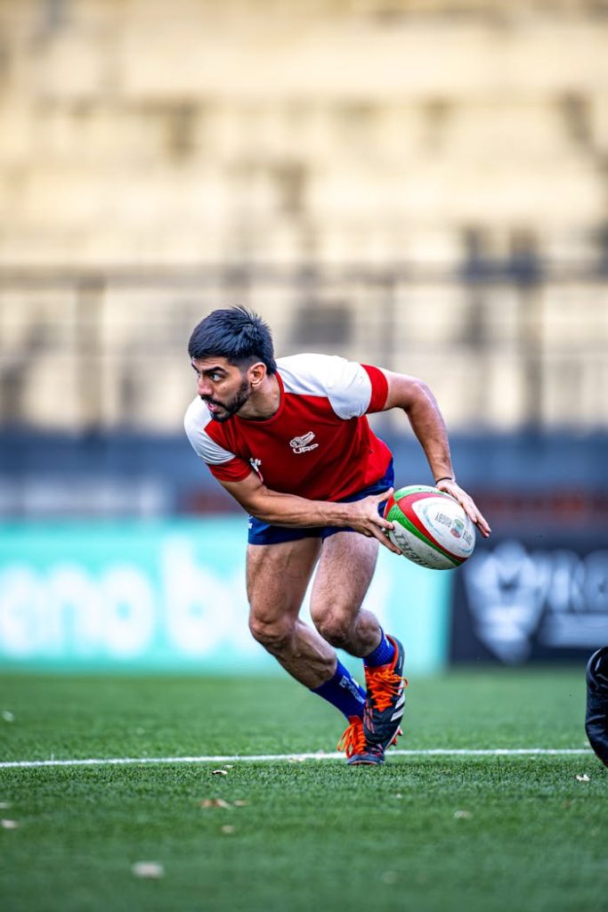 Intense rugby match with player running for a pass on the field.